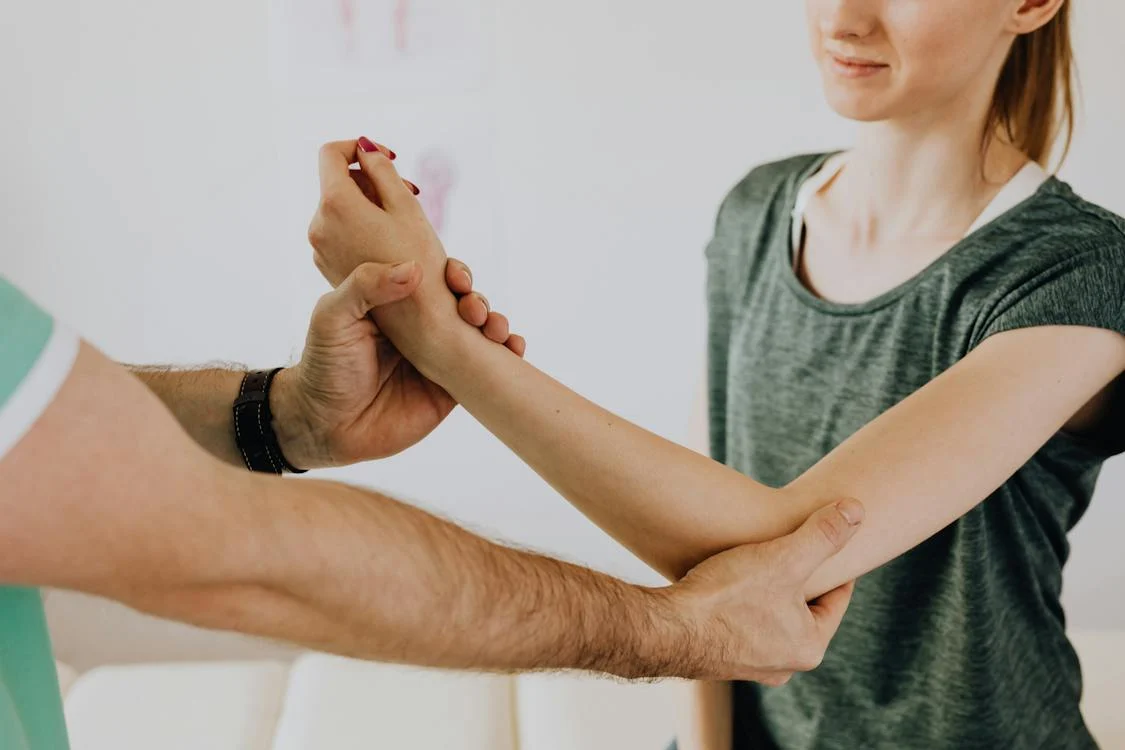 a doctor examining a patient elbow in his office